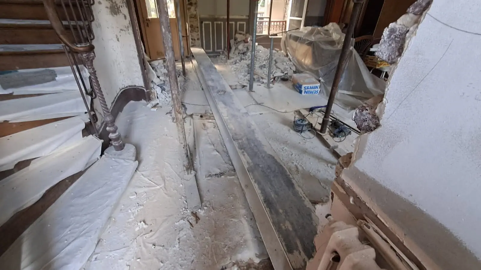 Intérieur de maison ancienne en cours de démolition, avec étaiement et escalier protégé
