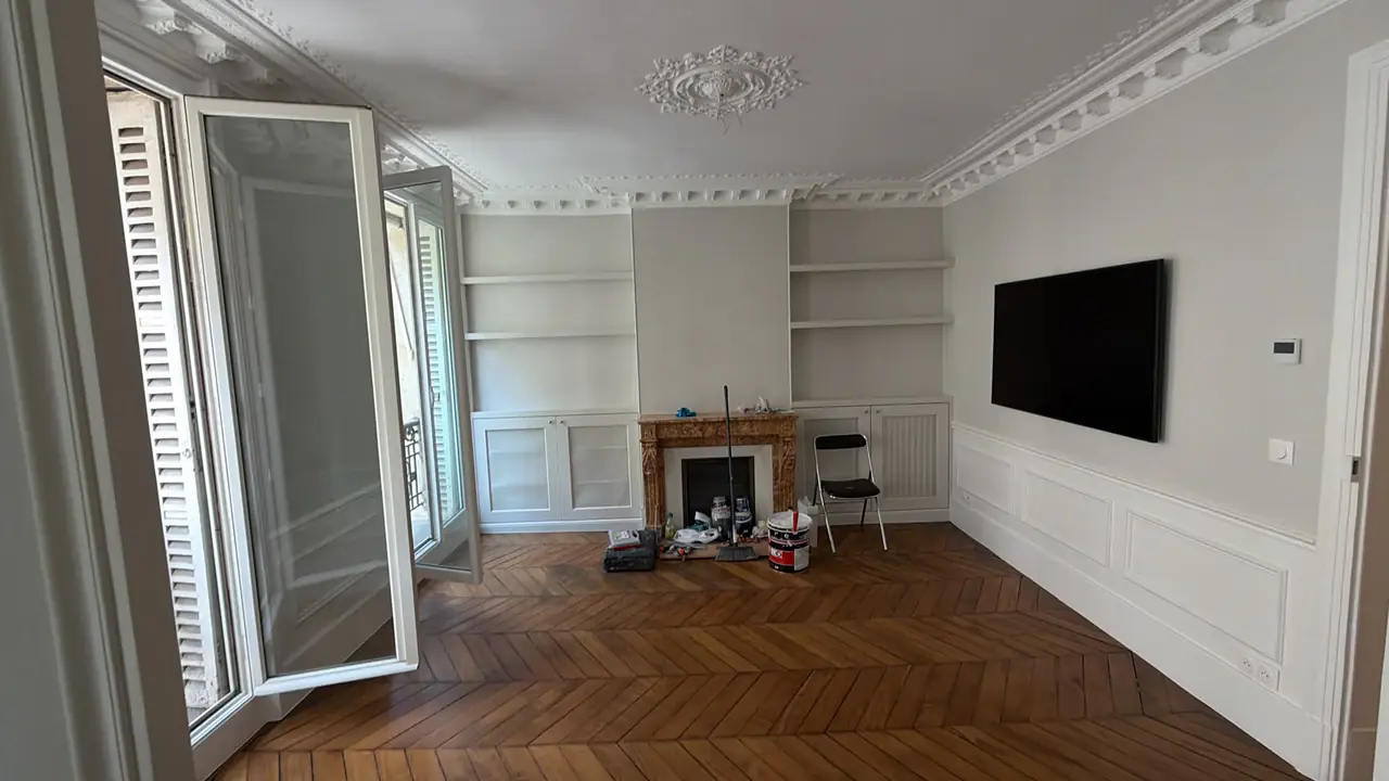 Salon avec parquet en point de Hongrie, cheminée, bibliothèque et moulures au plafond