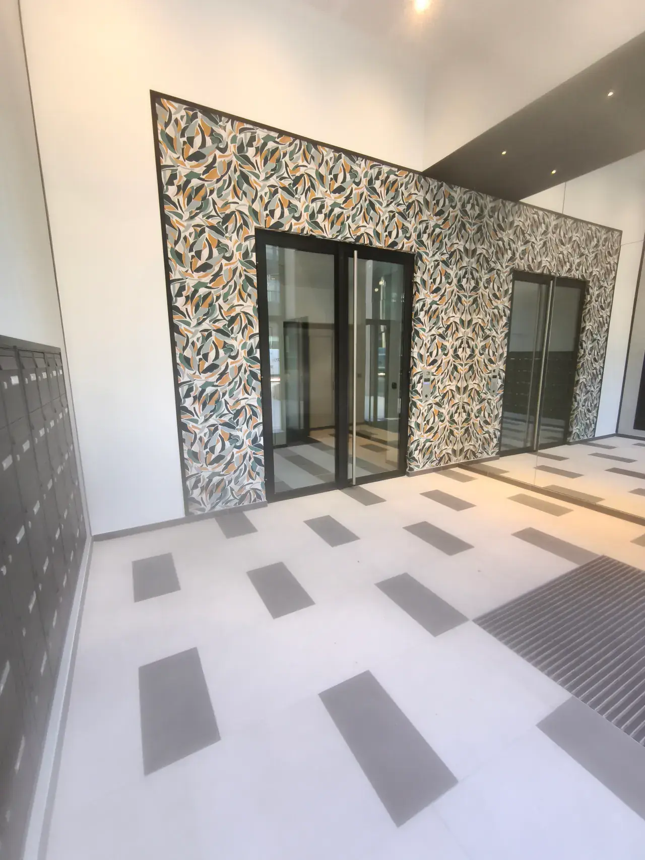 Entrée d'immeuble rénovée avec mur décoratif et sol carrelé