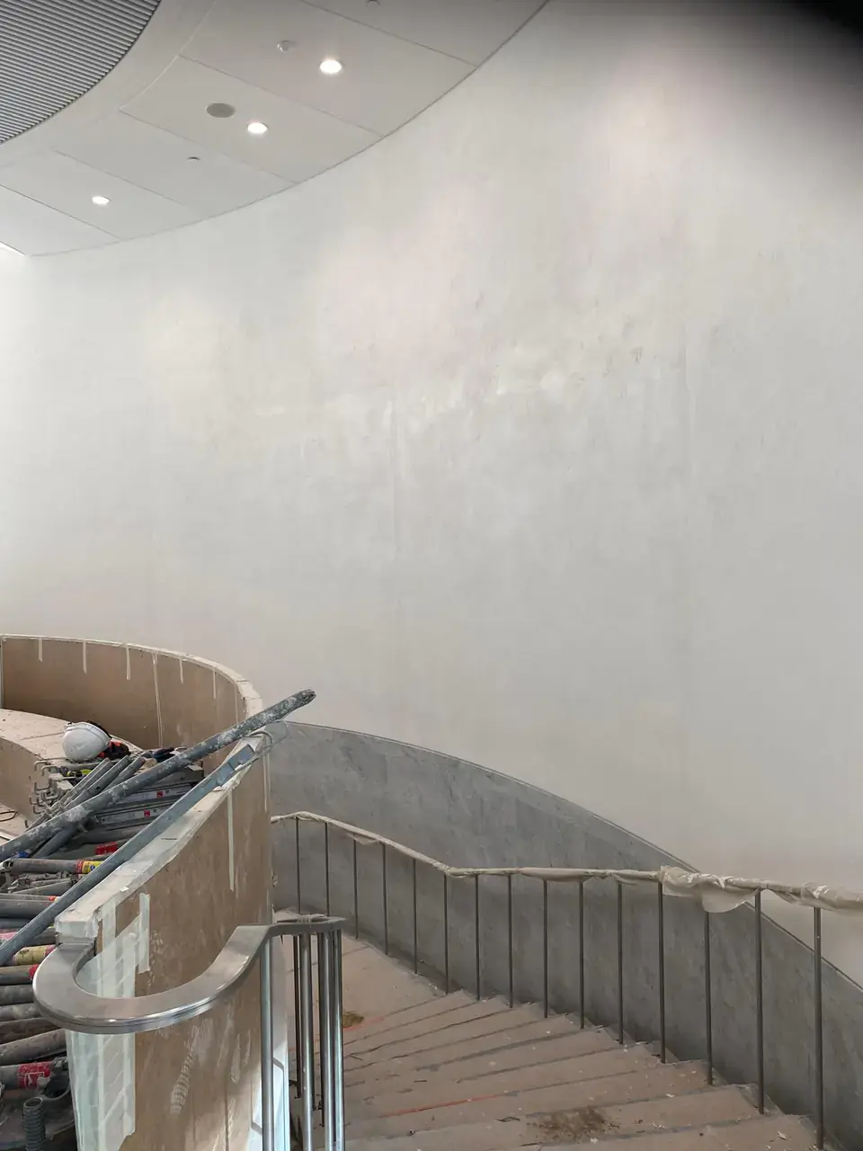 Escalier hélicoïdal en cours de finition, avec limon en marbre gris et garde-corps protégé