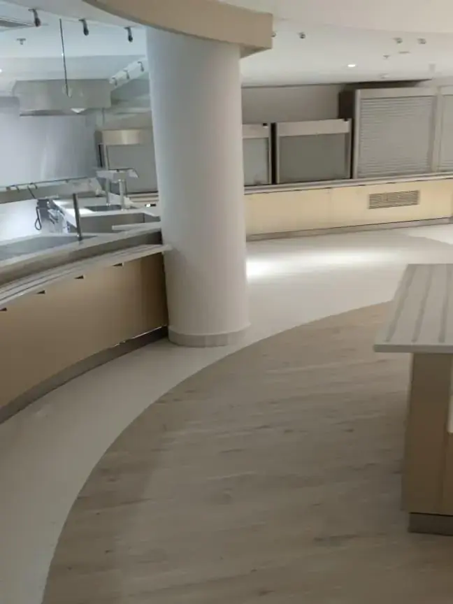 Comptoir de self en inox et bois avec sol en parquet clair découpé en courbe