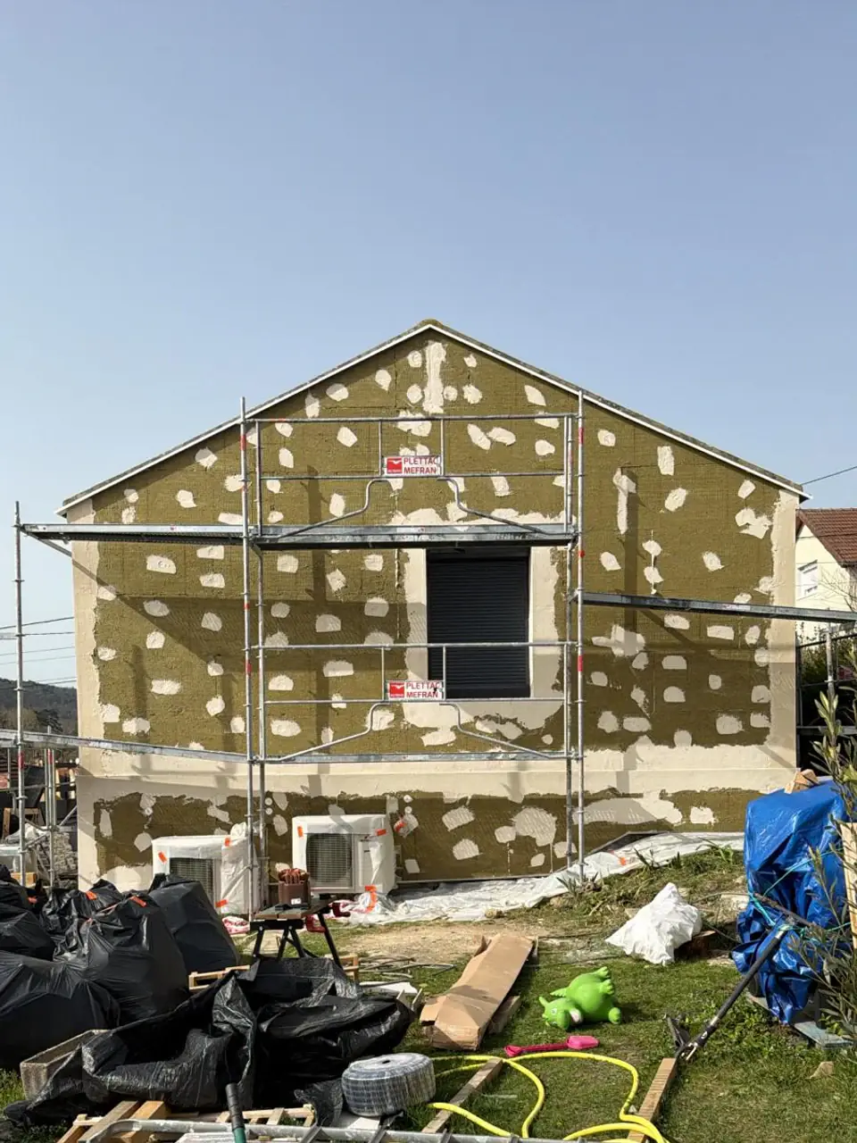 Pignon de maison couvert de panneaux d’isolation fixés avant la pose de l’enduit