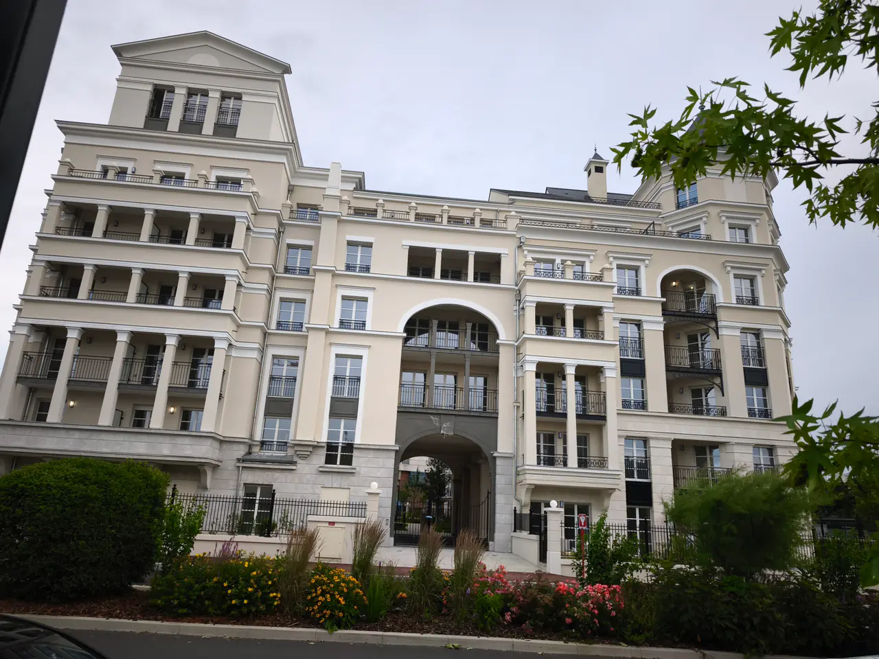 Façade claire de la résidence, avec porche central et balcons en ferronnerie