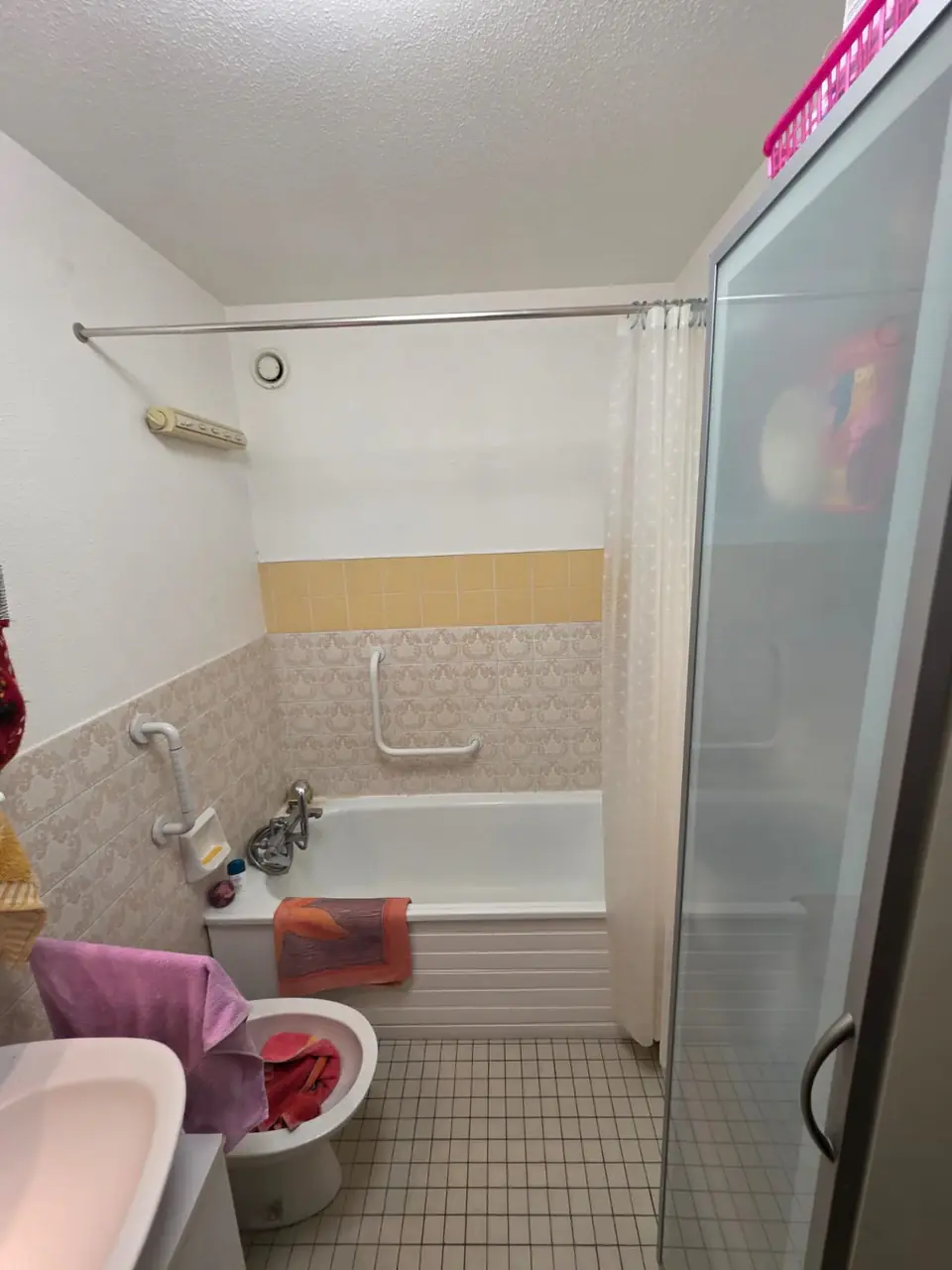 Salle de bains d’origine avec baignoire encastrée, rideau de douche et faïence beige à motifs