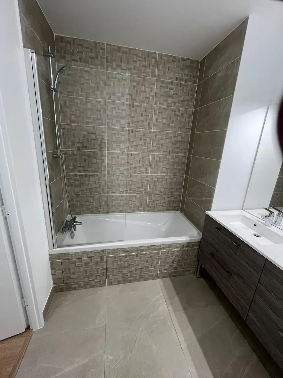 Baignoire avec pare-baignoire vitré, faïence à motif tressé et meuble vasque