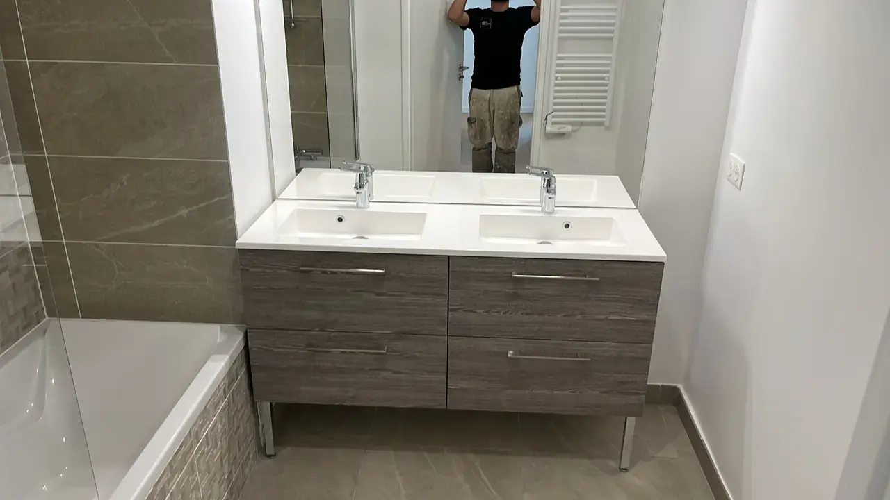 Meuble double vasque en bois foncé avec plan blanc, grand miroir et sèche-serviettes