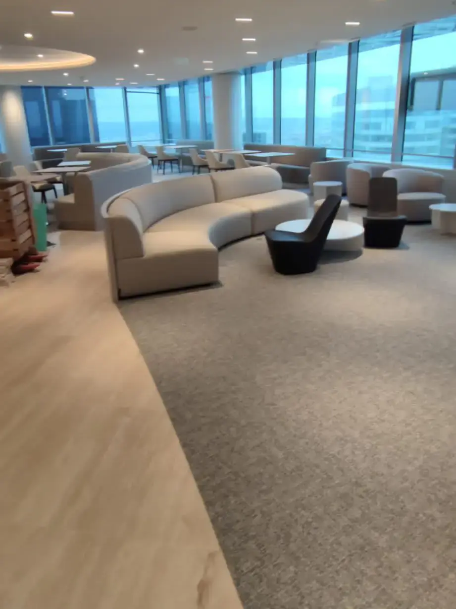 Espace de détente d’étage avec banquettes courbes, moquette et façade vitrée panoramique