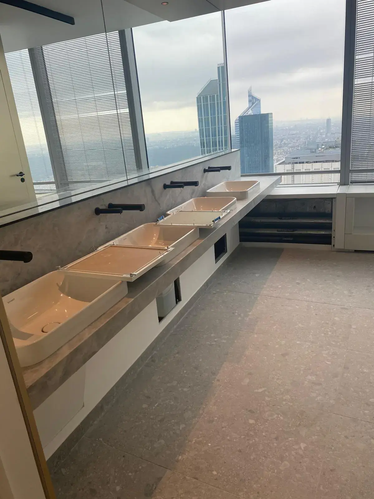 Sanitaires d’étage avec plans vasques en marbre, robinetterie noire et vue sur les tours