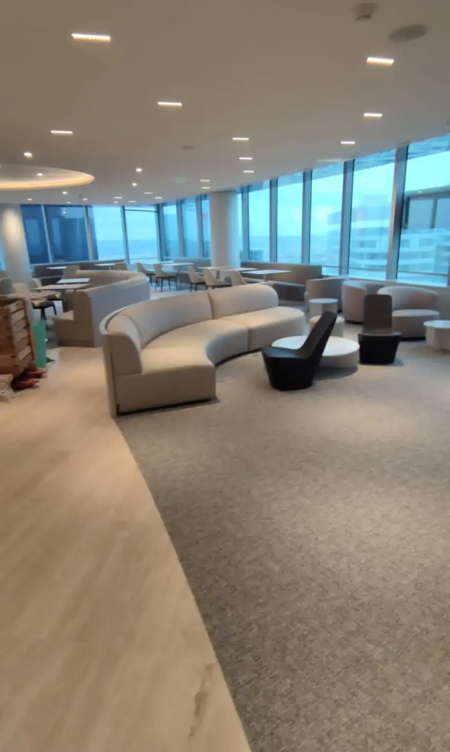 Espace de détente tertiaire aménagé avec canapés, tables, éclairage encastré et façade vitrée