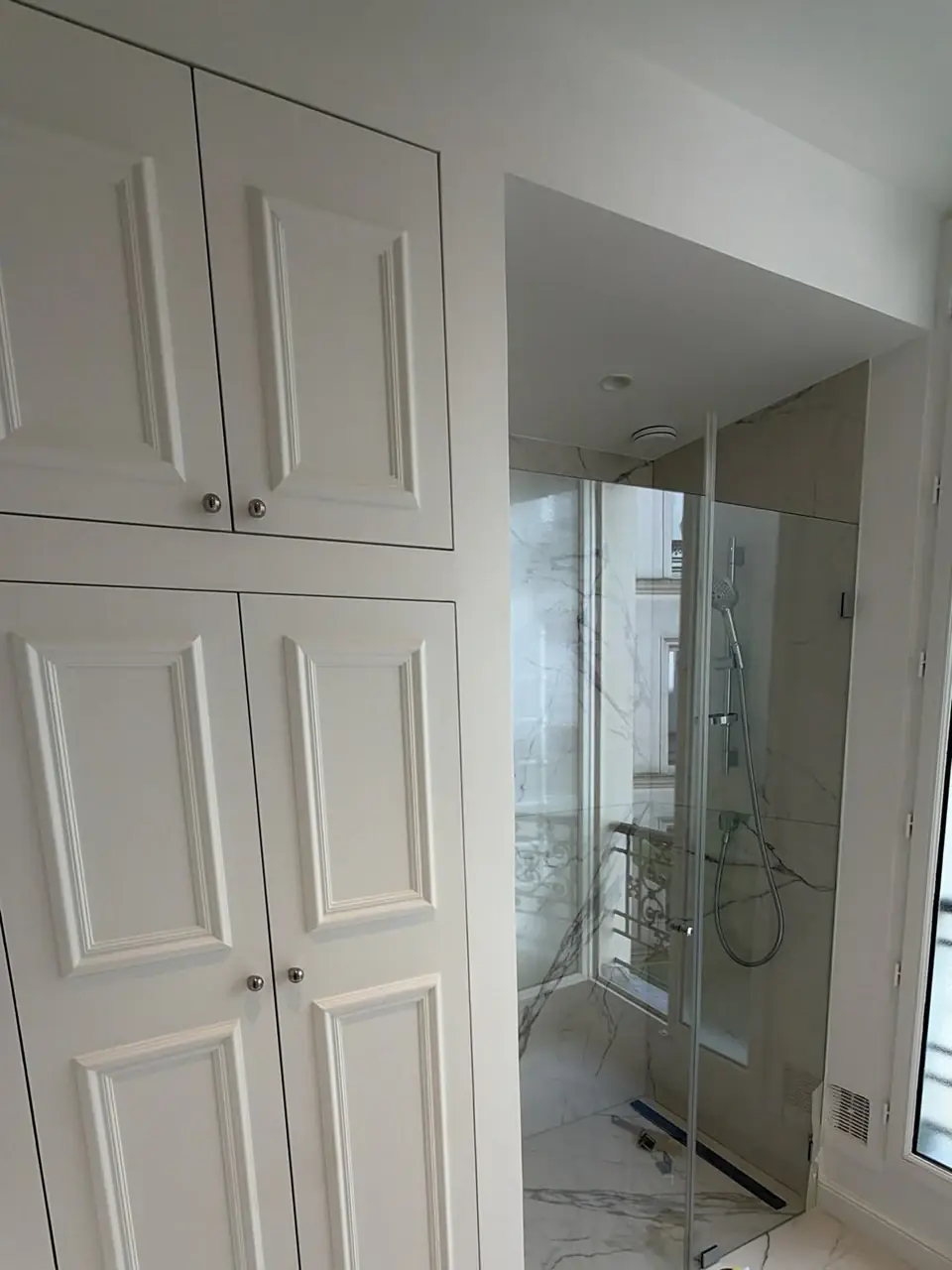 Douche à l’italienne avec revêtement grand format effet marbre et rangements moulurés